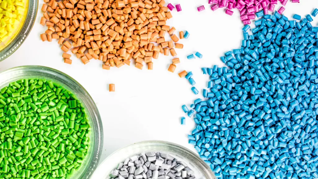 plastic chips A collection of different coloured plastic chips used as raw material in the production of plastic injection moulding both in bowls and spread out on surface.