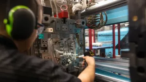 plastic injection moulding A man is fitting a plastic injection moulding tool into a mould machine.